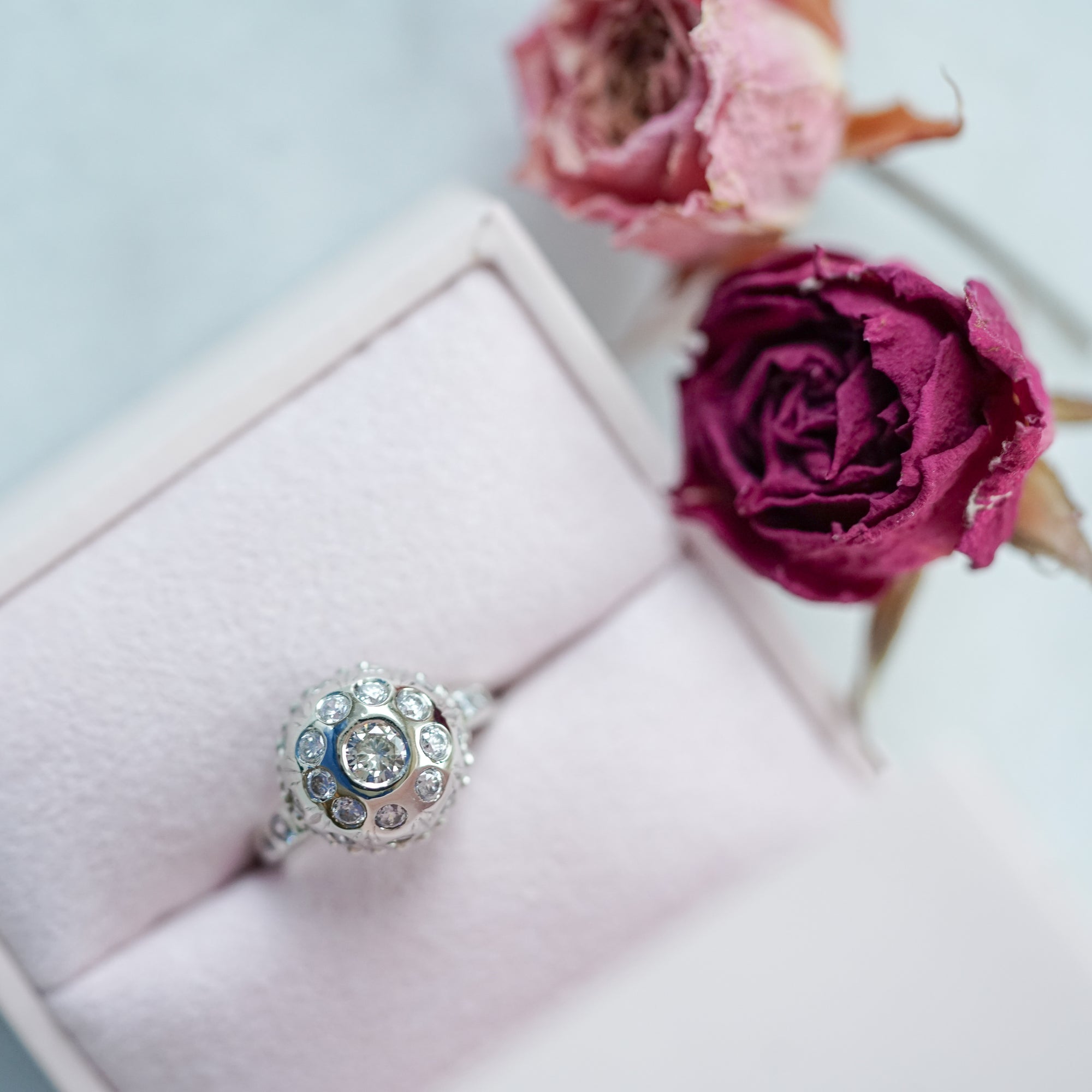 engagement ring with diamonds on a pink jewelry gift box with a red rose