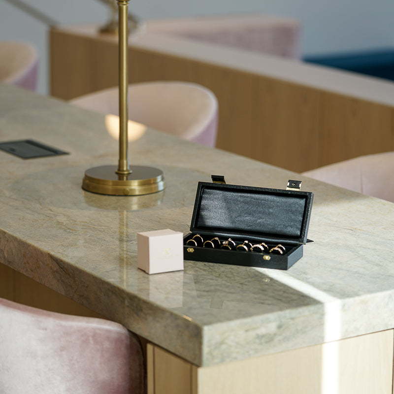 Jewelry box with many engagement rings is seating on a table with chairs