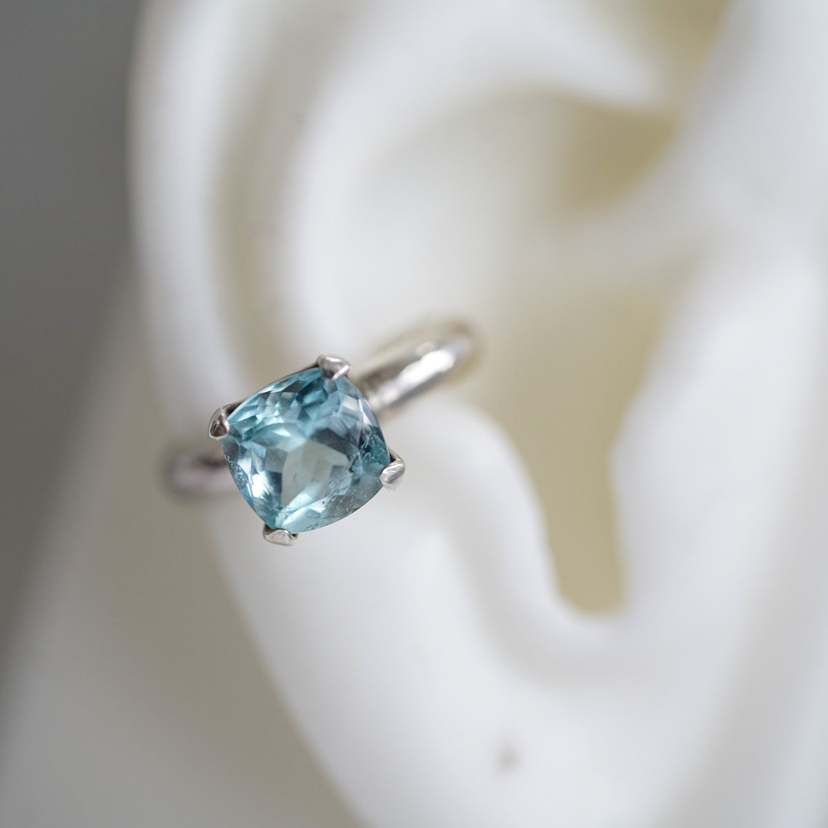 silver ear cuff with cushion blue topaz on a ear lobe