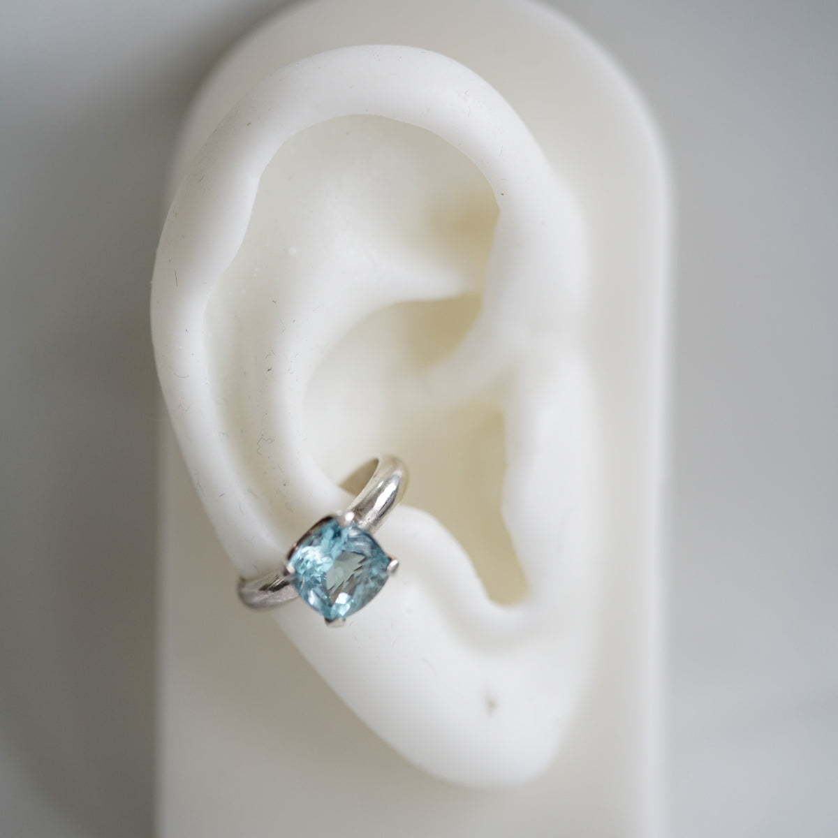 silver ear cuff with a blue topaz on a ear