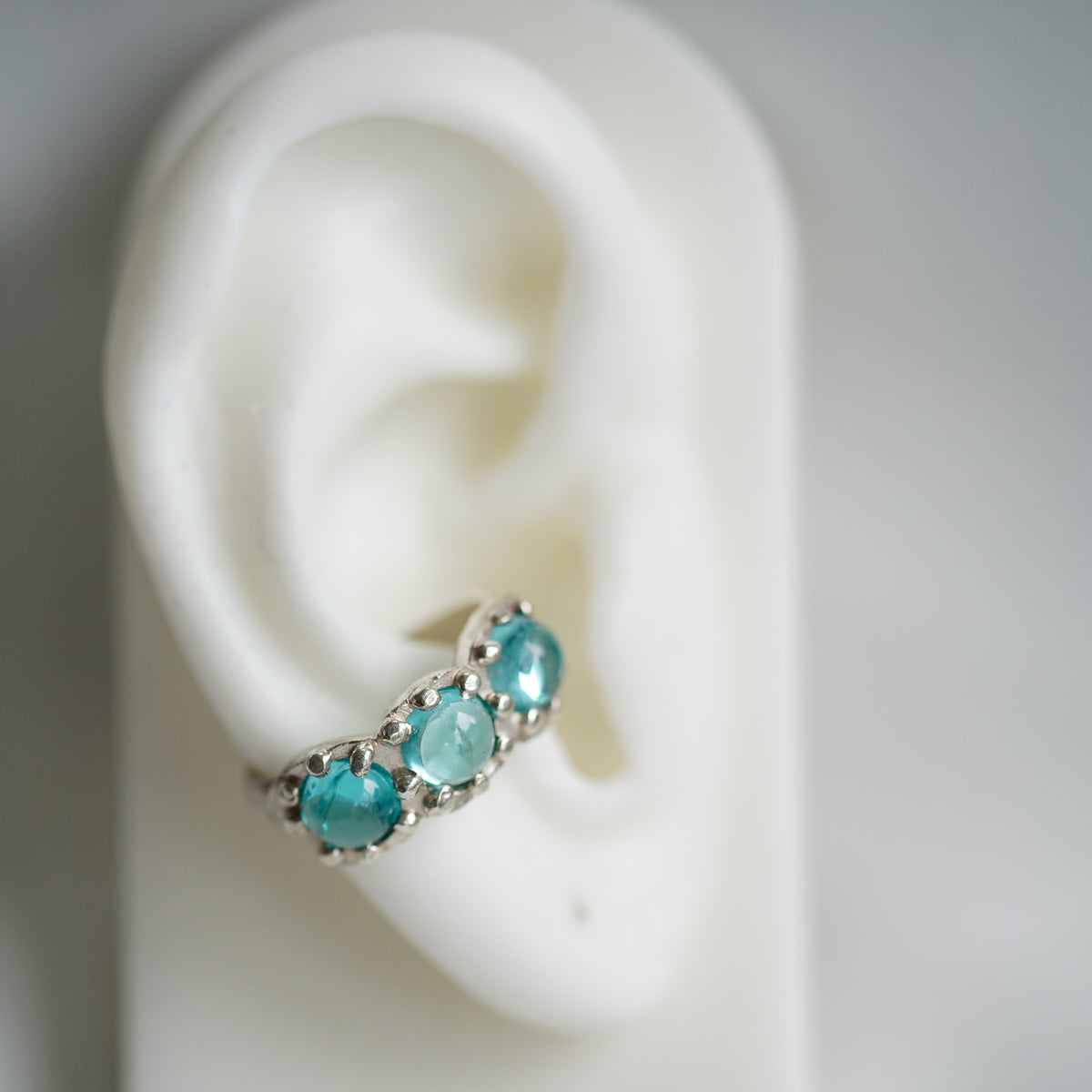 acfj silver ear cuff with blue topaz cabochons on a ear 